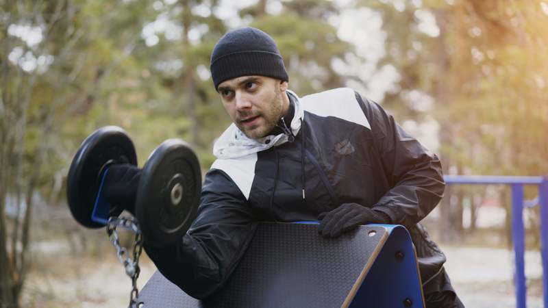 Man in his 40s lifting weights with focus in a well-lit home gym
